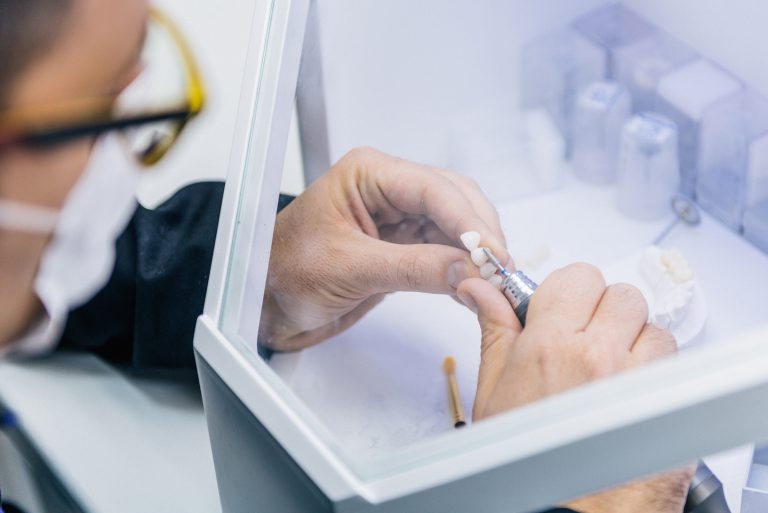 Close-up of dental technician shaping a dental crown in a laboratory setting