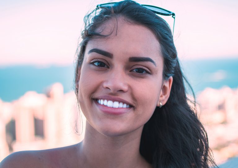 Young woman smiling confidently outside after successful dental extraction
