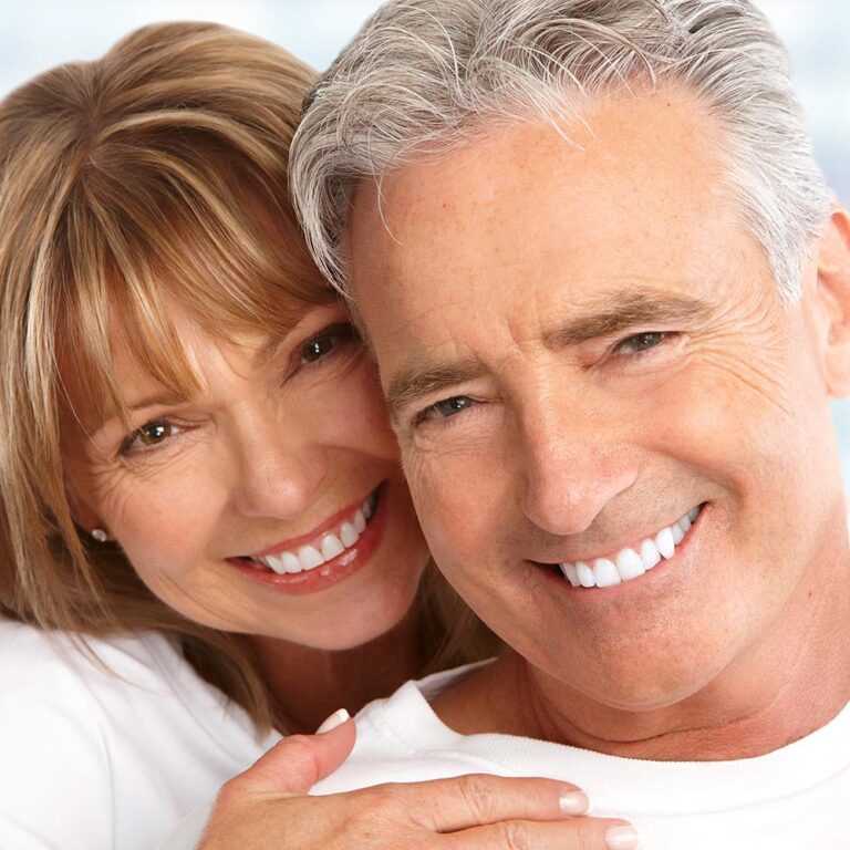 Happy senior couple showing off bright smiles after receiving dental implants
