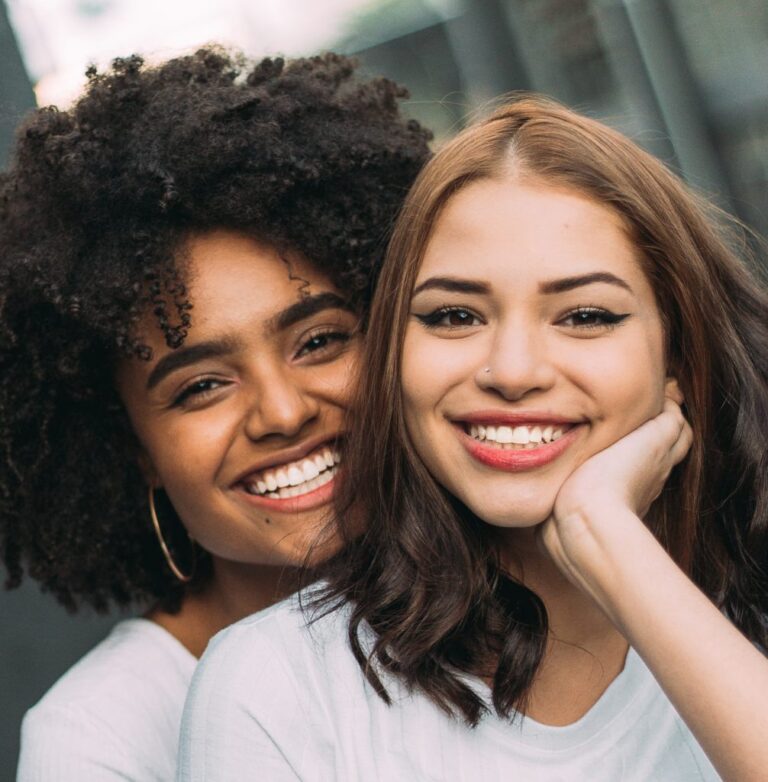 Two young women smiling confidently after dental treatment, possibly root canal