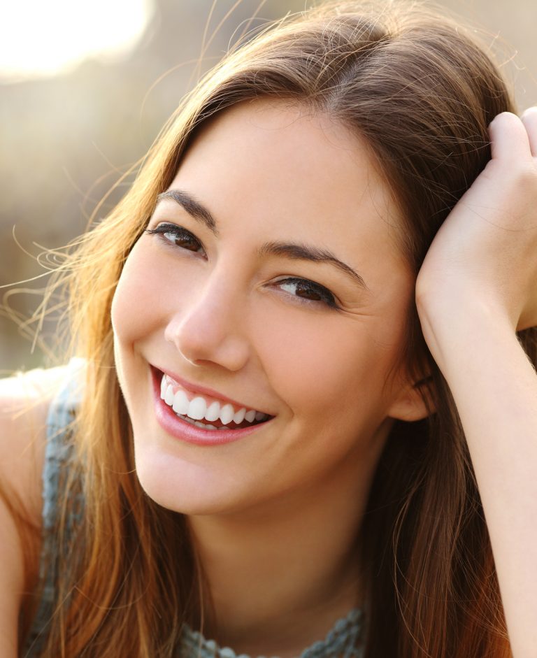 Young woman showing off her bright, even smile after getting dental veneers